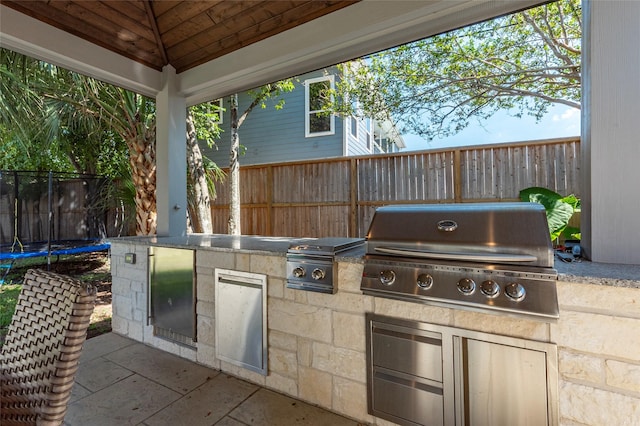 view of patio featuring a trampoline, fence, and area for grilling