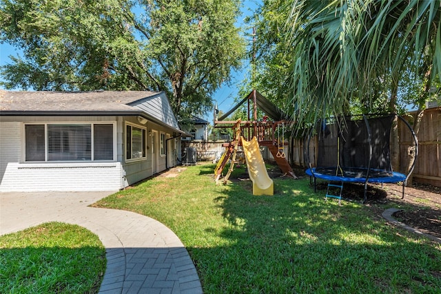 view of yard featuring a trampoline, a playground, and a fenced backyard