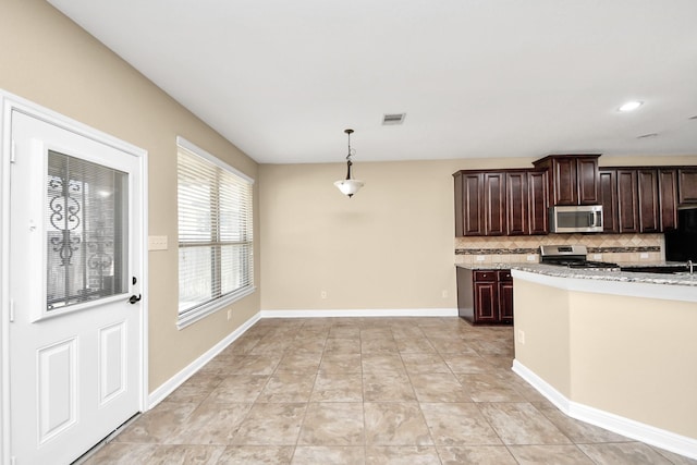 kitchen with dark brown cabinetry, visible vents, baseboards, appliances with stainless steel finishes, and backsplash