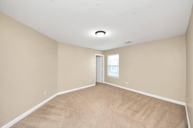 unfurnished room featuring visible vents, baseboards, and light colored carpet