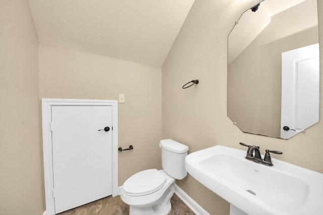 bathroom with vaulted ceiling, a sink, toilet, and baseboards