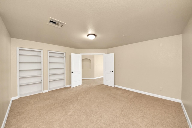 unfurnished bedroom with light carpet, baseboards, visible vents, and a textured ceiling