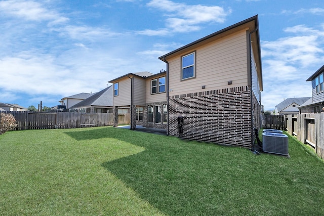 back of house featuring central AC, a lawn, and a fenced backyard