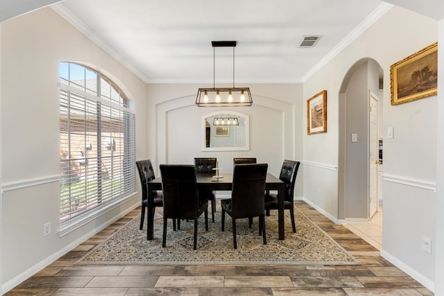 dining area with wood finish floors, visible vents, arched walkways, and crown molding