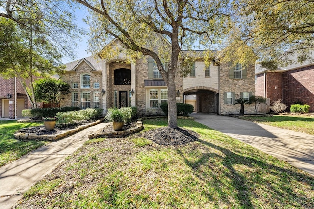 view of front of house with brick siding, a front lawn, and a gate