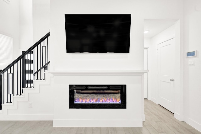 interior details featuring a glass covered fireplace, baseboards, and wood finished floors