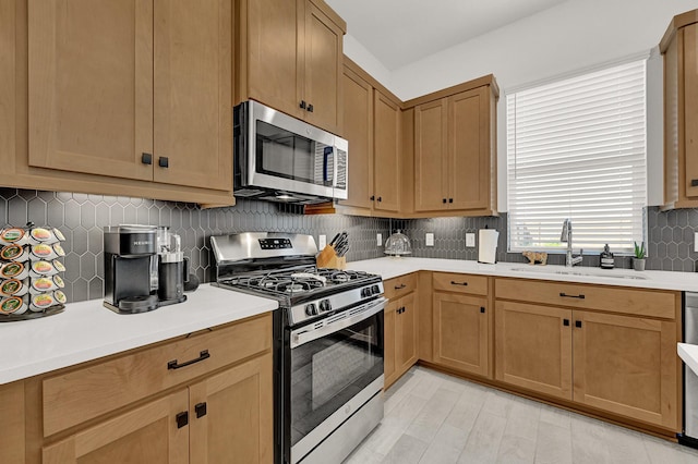 kitchen with light countertops, appliances with stainless steel finishes, backsplash, and a sink