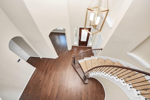 entryway with stairway, wood finished floors, a towering ceiling, and baseboards