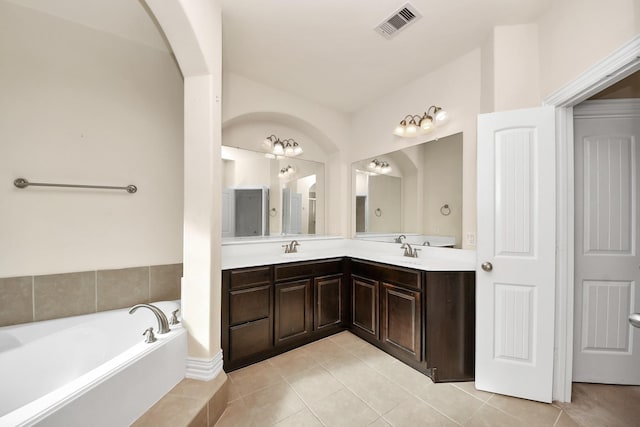 full bathroom with tile patterned flooring, a sink, visible vents, a bath, and double vanity