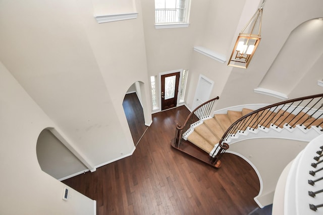 foyer featuring stairs, a towering ceiling, wood finished floors, and a wealth of natural light