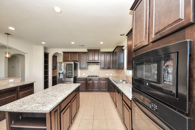 kitchen with arched walkways, open shelves, appliances with stainless steel finishes, a sink, and dark brown cabinetry