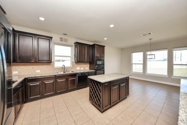 kitchen featuring a sink, visible vents, a center island, black appliances, and tasteful backsplash