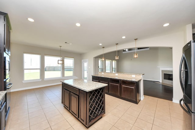 kitchen featuring a fireplace, light tile patterned floors, visible vents, freestanding refrigerator, and a kitchen island