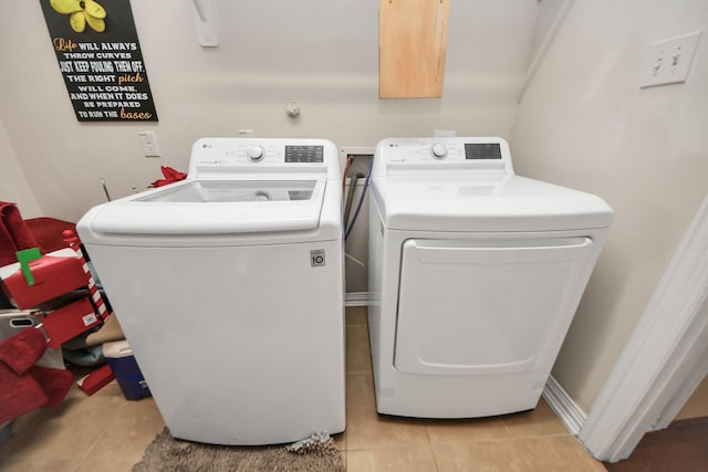 laundry area with light tile patterned floors, laundry area, baseboards, and washer and dryer