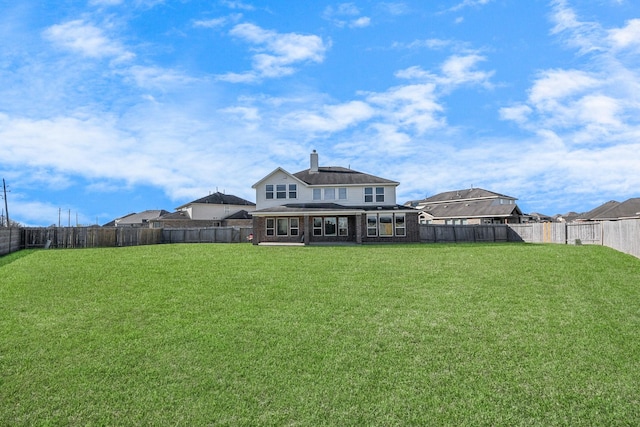 back of house featuring a fenced backyard, a lawn, and a chimney