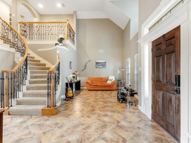 foyer entrance with stairway, a high ceiling, and baseboards