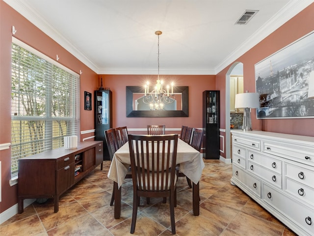 dining room featuring an inviting chandelier, crown molding, visible vents, and arched walkways