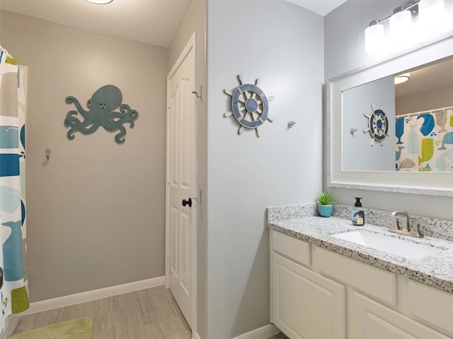 bathroom with baseboards, a shower with curtain, wood finished floors, and vanity