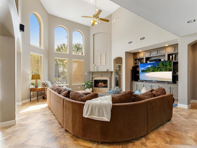 living room with baseboards, a ceiling fan, visible vents, and a premium fireplace