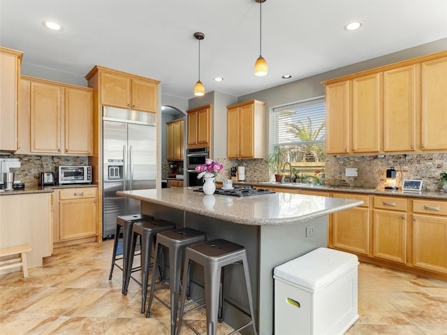 kitchen with stainless steel appliances, a kitchen island, and light brown cabinetry