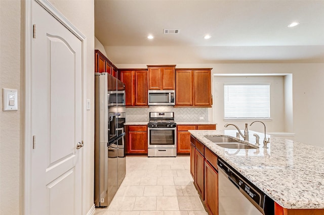 kitchen with light stone counters, a sink, visible vents, appliances with stainless steel finishes, and backsplash