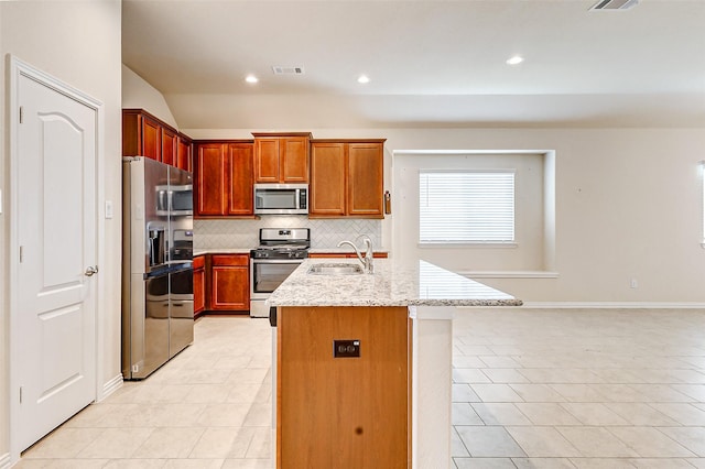 kitchen featuring a sink, visible vents, appliances with stainless steel finishes, backsplash, and light stone countertops