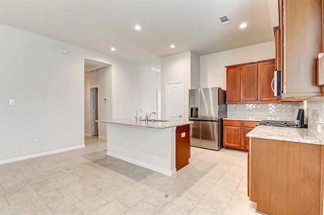 kitchen featuring visible vents, a kitchen island with sink, appliances with stainless steel finishes, and light stone counters