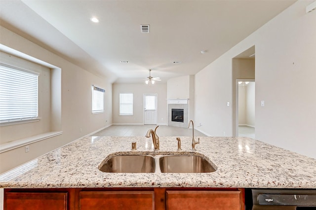 kitchen featuring a fireplace, a sink, visible vents, open floor plan, and a center island with sink