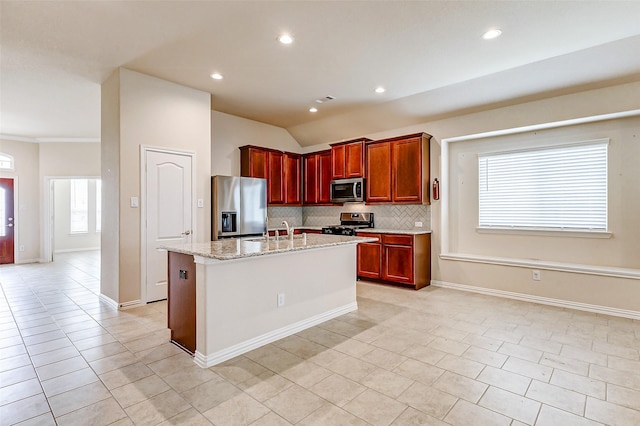 kitchen with light tile patterned floors, a center island with sink, a sink, stainless steel appliances, and backsplash