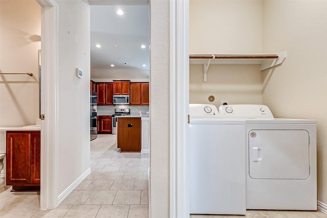 clothes washing area featuring light tile patterned floors, recessed lighting, washing machine and dryer, a sink, and laundry area