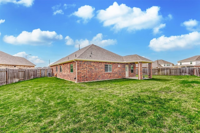 back of house featuring a yard, a fenced backyard, and brick siding