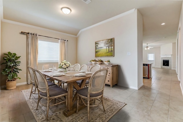 dining area featuring baseboards, a healthy amount of sunlight, a fireplace, and crown molding