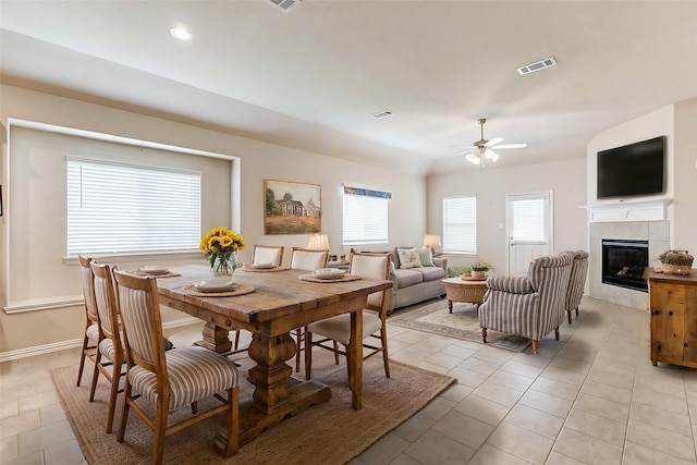 dining space featuring light tile patterned flooring, ceiling fan, visible vents, and a tile fireplace