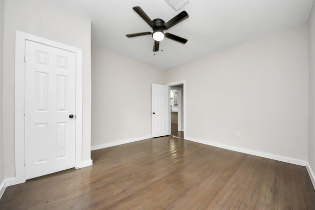 empty room with hardwood / wood-style flooring, baseboards, visible vents, and ceiling fan