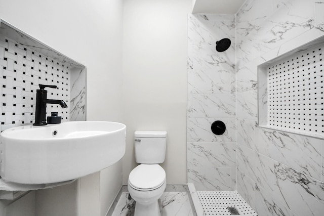 full bath featuring toilet, a sink, baseboards, marble finish floor, and a tile shower