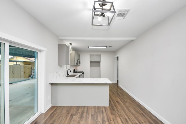 kitchen with visible vents, dark wood-style floors, a peninsula, gray cabinetry, and a sink