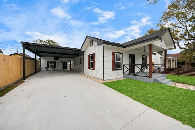 view of front facade with covered porch, driveway, an attached carport, and fence