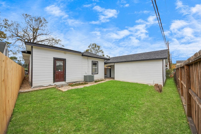 rear view of property featuring cooling unit, a fenced backyard, a yard, and an outdoor structure