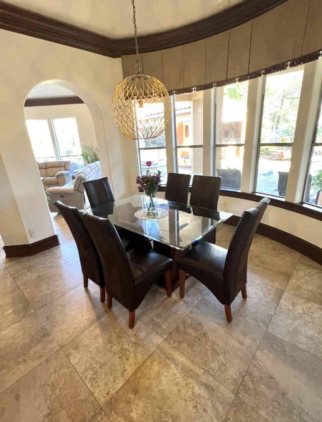 dining area with baseboards, arched walkways, and crown molding