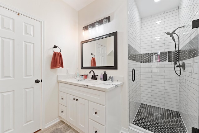 bathroom with double vanity, a stall shower, a sink, and baseboards