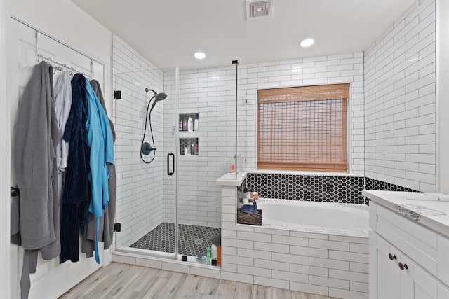 full bath featuring a garden tub, wood finished floors, vanity, visible vents, and a stall shower