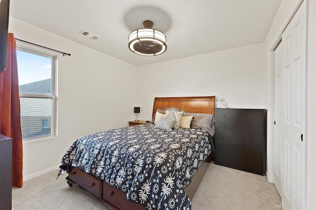 carpeted bedroom with a closet, visible vents, and baseboards