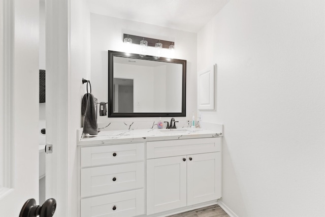 bathroom with vanity, baseboards, and wood finished floors