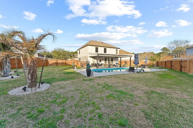 rear view of property featuring a yard, a fenced in pool, a fenced backyard, and a patio