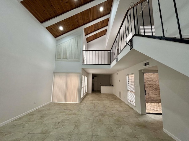 unfurnished living room with beam ceiling, a wealth of natural light, visible vents, wood ceiling, and baseboards