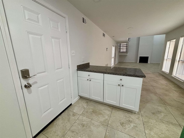 kitchen with light tile patterned floors, a peninsula, visible vents, white cabinets, and open floor plan