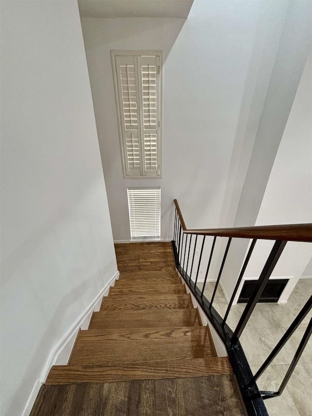 stairs with baseboards, visible vents, and wood finished floors