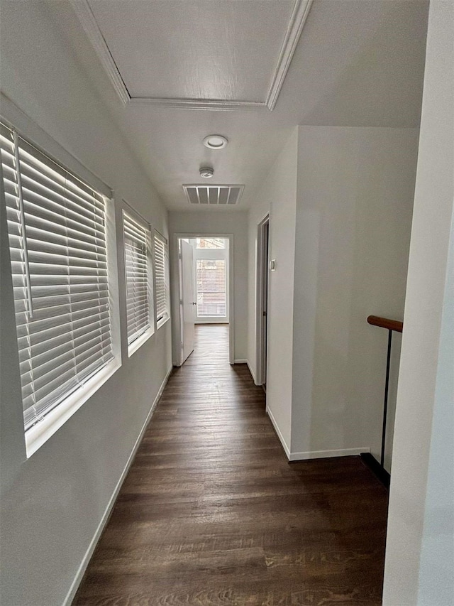 corridor with dark wood-type flooring, visible vents, and baseboards