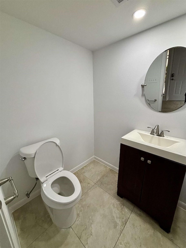 bathroom featuring toilet, baseboards, and vanity