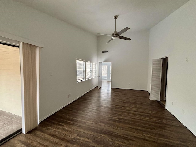 interior space with baseboards, visible vents, dark wood finished floors, a ceiling fan, and high vaulted ceiling